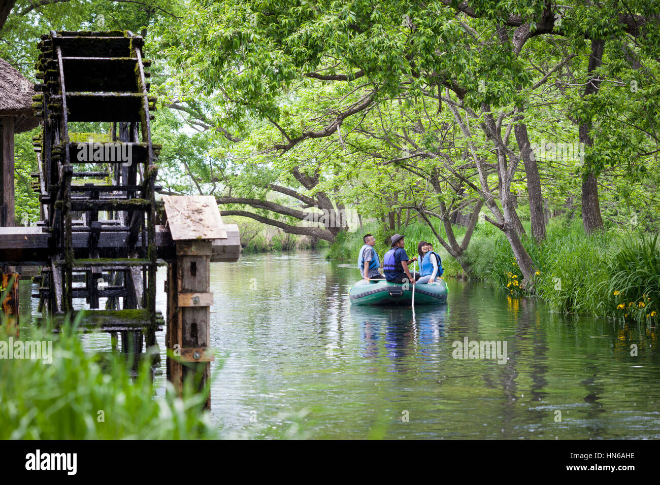 AZUMINO, JAPAN - MAY 14: Tourists on a boat trip down the Yorozui river pass a wooden watermill at Daio Wasabi Farm, Azumino on 14th May 2012. Daio is Stock Photo