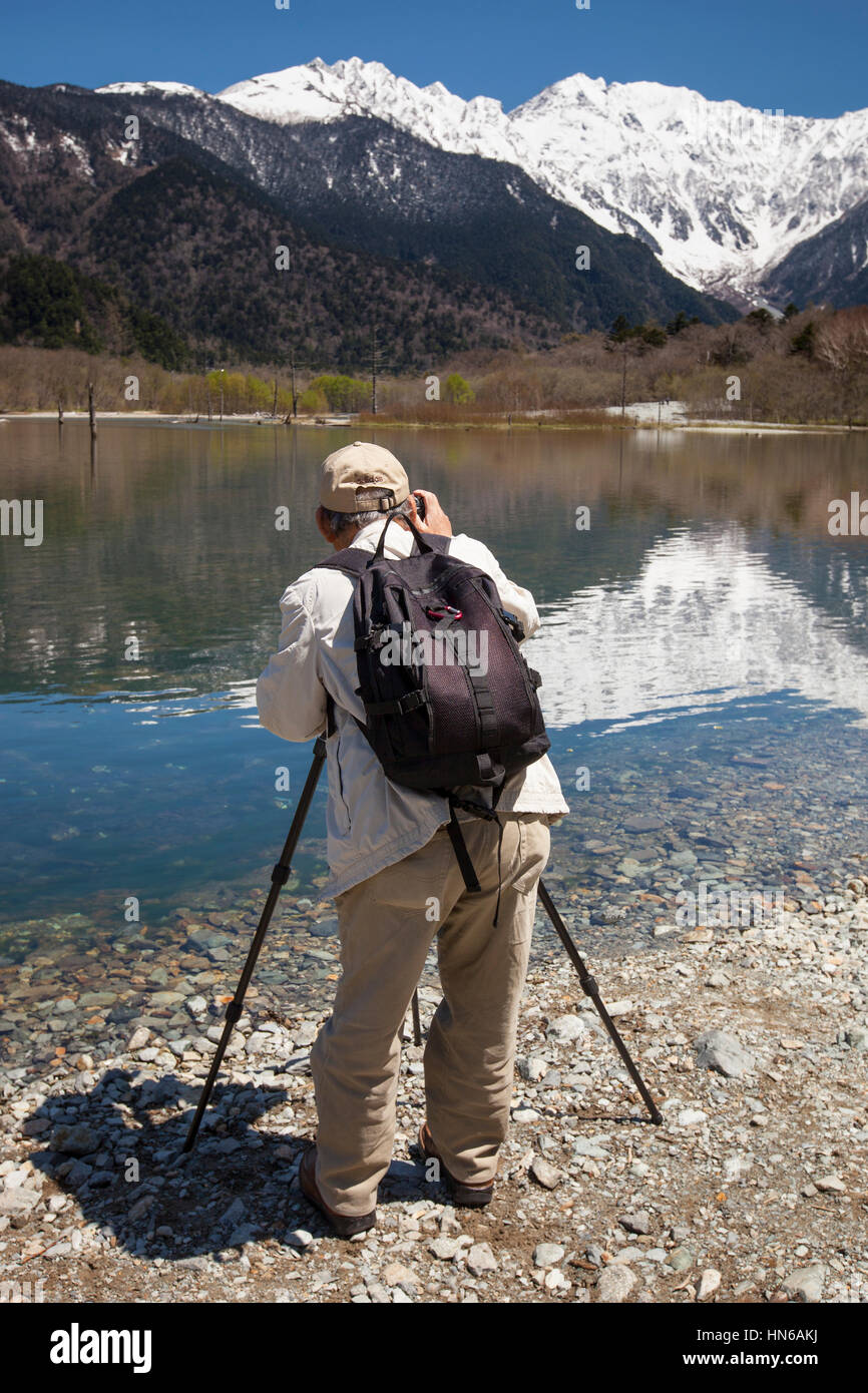 Kamikochi, Japan - May 19, 2012: Back view of a man photographing the beautiful mountain and lake scenery at Kamikochi in Japan's Northern Alps. Stock Photo