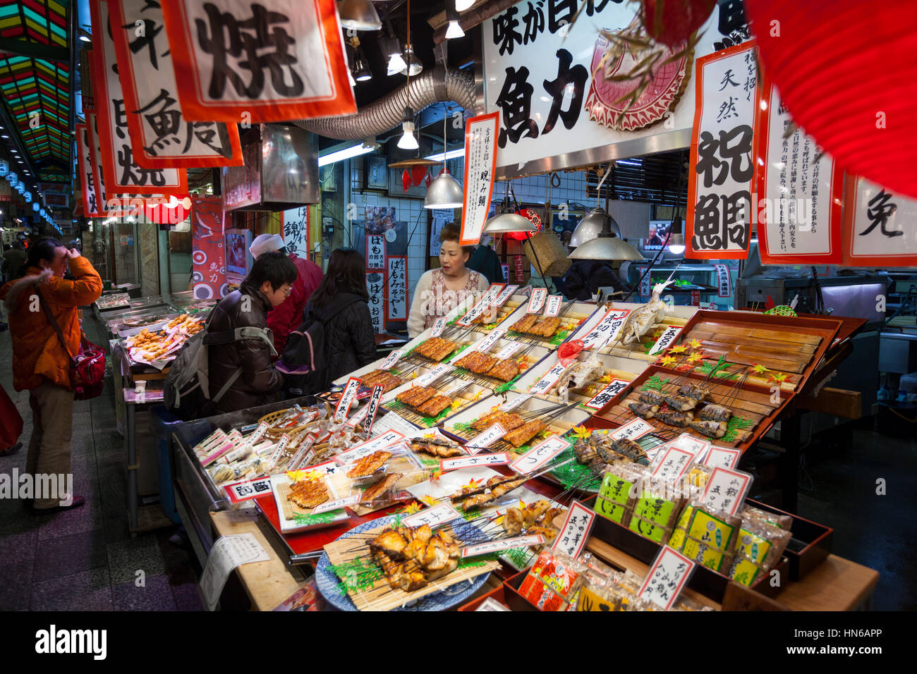 KYOTO, JAPAN - MARCH 23: Staff and customers at a stall selling cooked fish in Nishiki food market in Central Kyoto on 23rd March 2012. Stock Photo