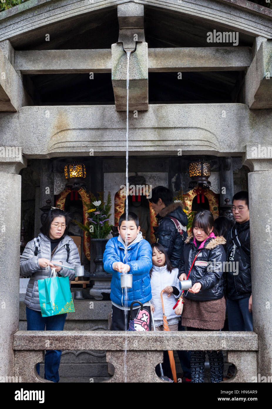 Kyoto, Japan - March 24, 2012: People collecting water from the Otowa-no-taki waterfall at Kiyomizu temple in Kyoto. Visitors drink the water which is Stock Photo