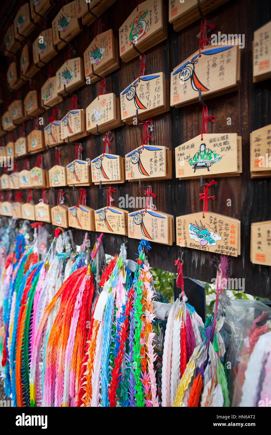 Kyoto, Japan - March 18, 2012: Close-up of prayer tablets and chains of paper origami cranes hanging at a Shinto shrine. The small wooden tablets, cal Stock Photo