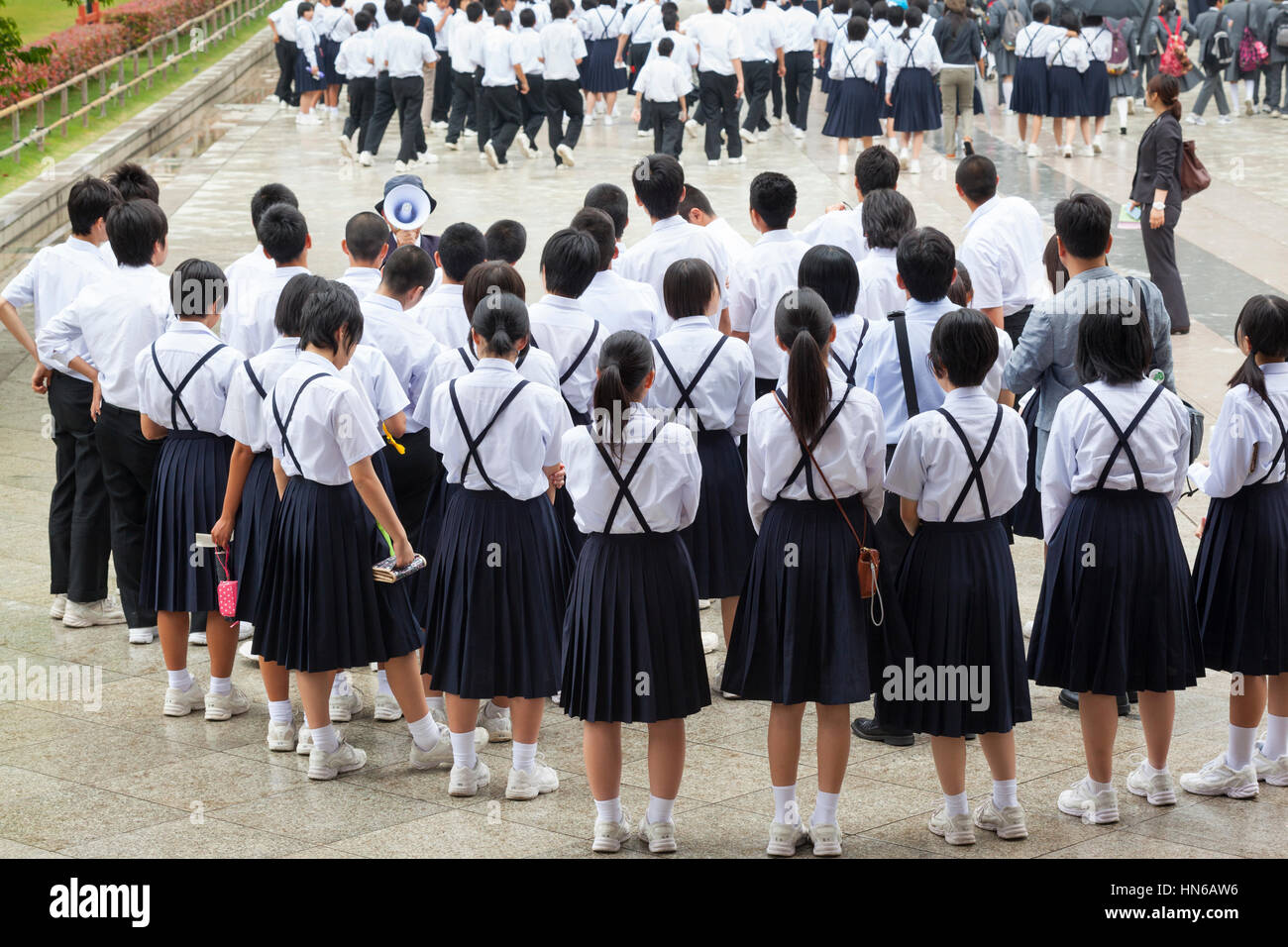Nara, Japan - May 9, 2012: A large group of Japanese school children in uniforms and a guide with a loud hailer on a school trip to Todai-ji temple in Stock Photo