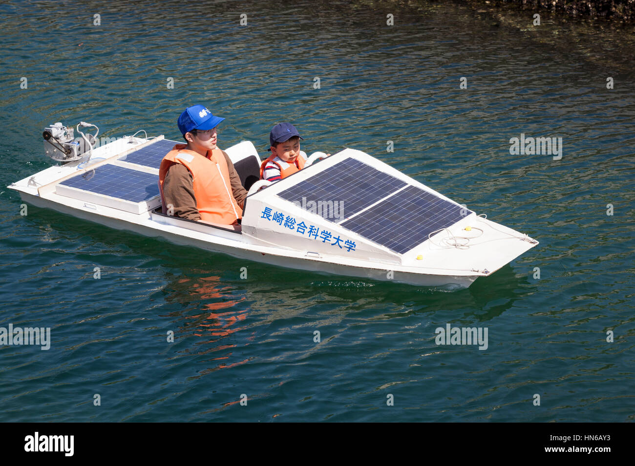 Nagasaki, Japan - April 28, 2012: A man and young boy sail a small solar powered boat on a calm waterway at Nagasaki waterfront. Children were allowed Stock Photo