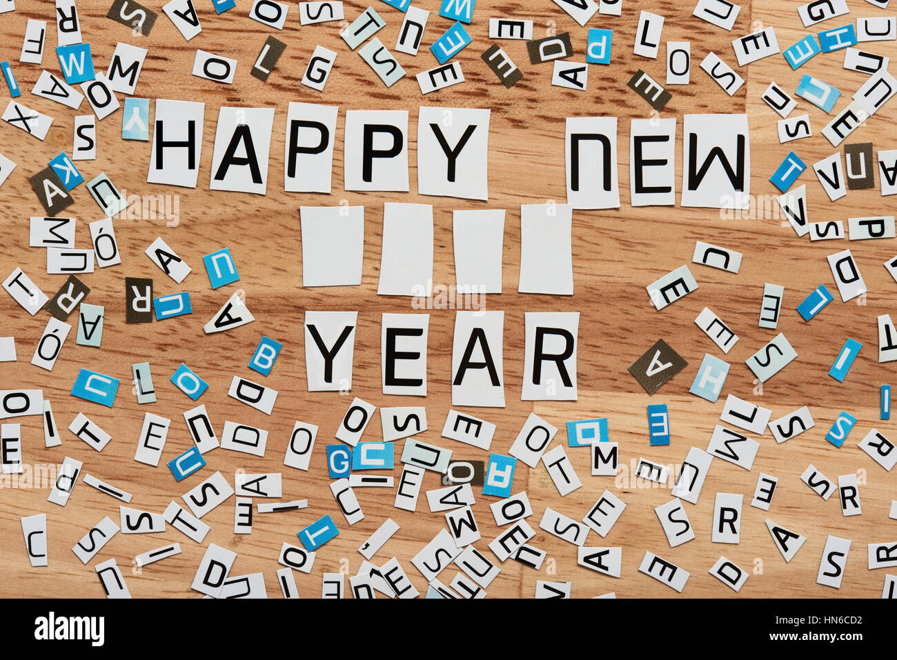 happy  new year word cut out from magazine on wood background Stock Photo