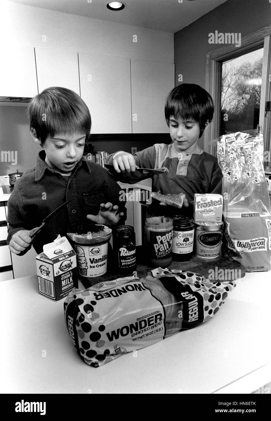 Young boys make peanut butter and jelly sandwiches using named brand grocery products including Wonder bread and Peter Pan peanut butter in a home kitchen. The FDA helps assure the quality of foods by setting standards spelling out the mandatory and optional ingredients in common foods and requires labeling using common names. Stock Photo