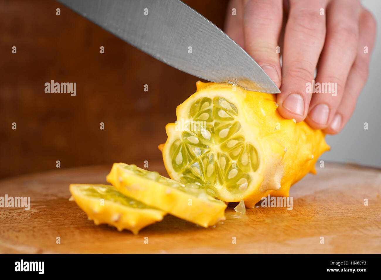https://c8.alamy.com/comp/HN6EY3/close-up-of-chefs-hands-cutting-kiwano-melon-on-a-wooden-cutting-board-HN6EY3.jpg