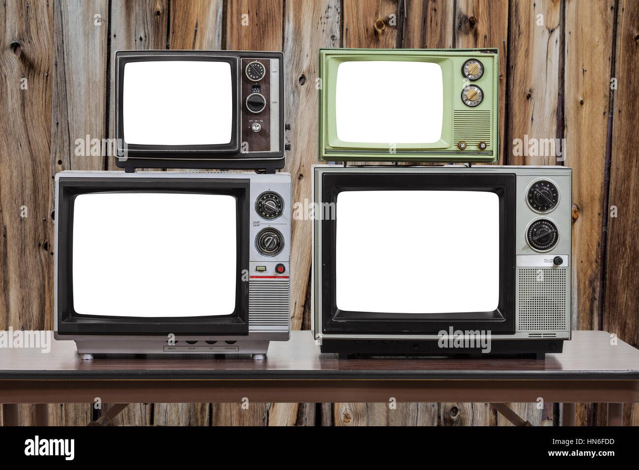 Four vintage televisions with cut out screens and old wood wall. Stock Photo