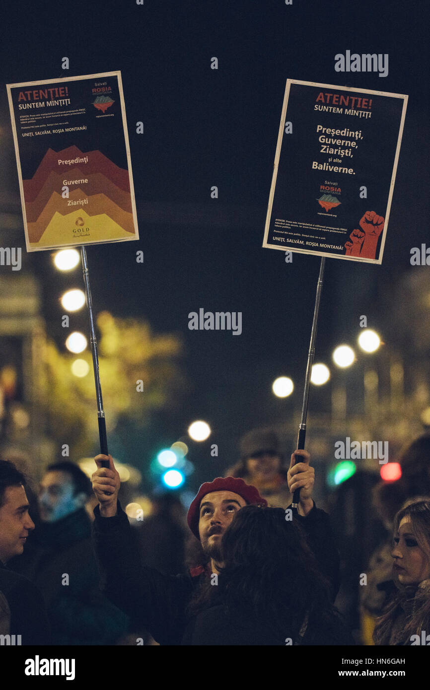 Bucharest, Romania - October 6, 2013: Young man holds two protest signs during the mass rally against the cyanide gold extraction in Rosia Montana Stock Photo