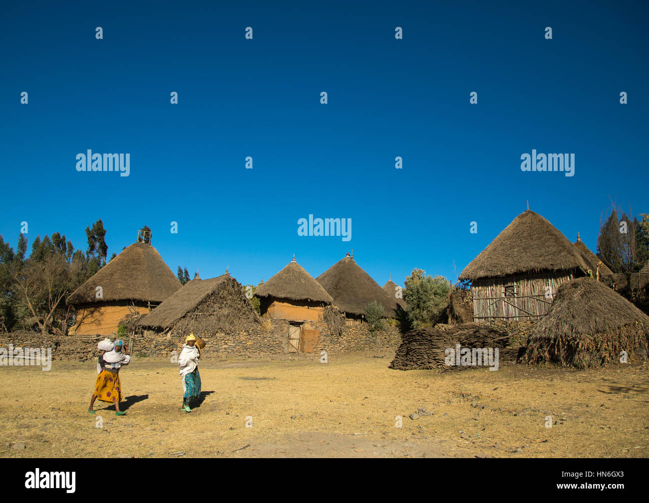 Two ethiopian women passing in front of stone houses village in the highlands, Amhara region, Debre Birhan, Ethiopia Stock Photo