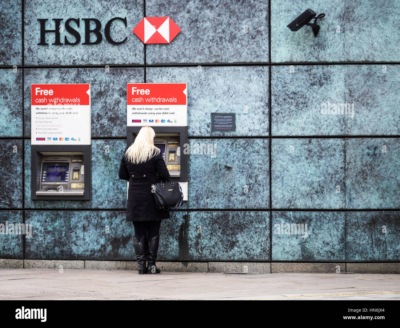 HSBC Cash Machines London - A woman uses a HSBC cash machines in Central London with security cameras monitoring the ATMs. Stock Photo