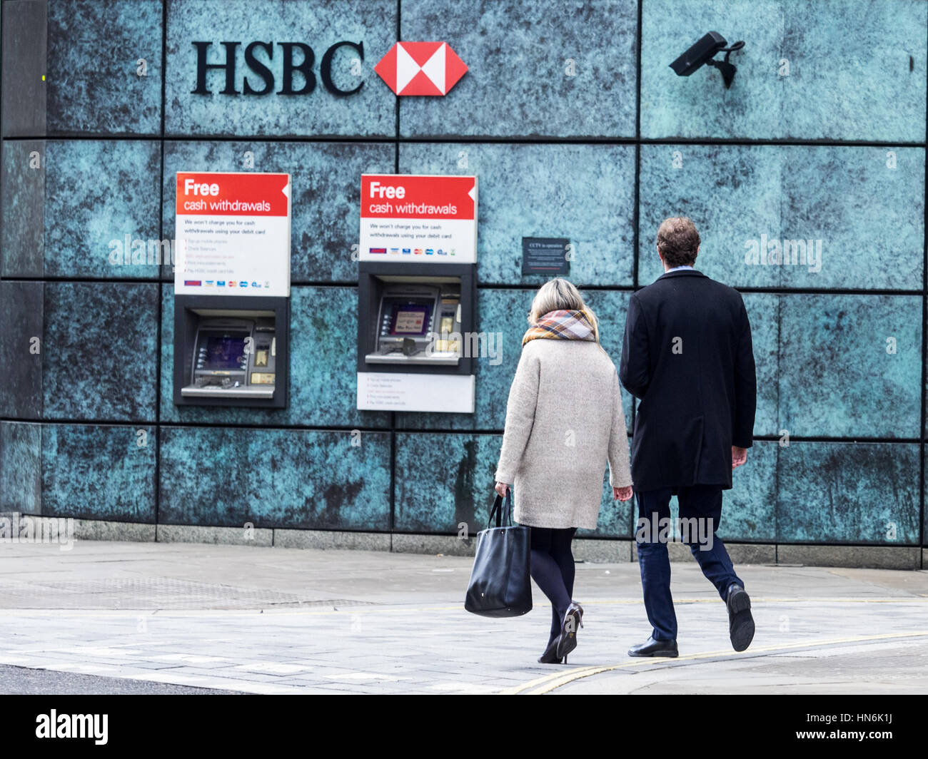 Bank Cash Machines - HSBC Cash Machines London - A couple walk towards HSBC cash machines in Central London with security cameras monitoring the ATMs. Stock Photo
