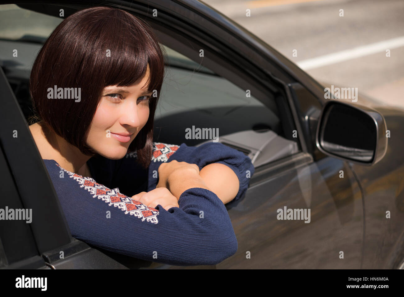 Young woman with burgundy hair looking out of right passanger window of ...
