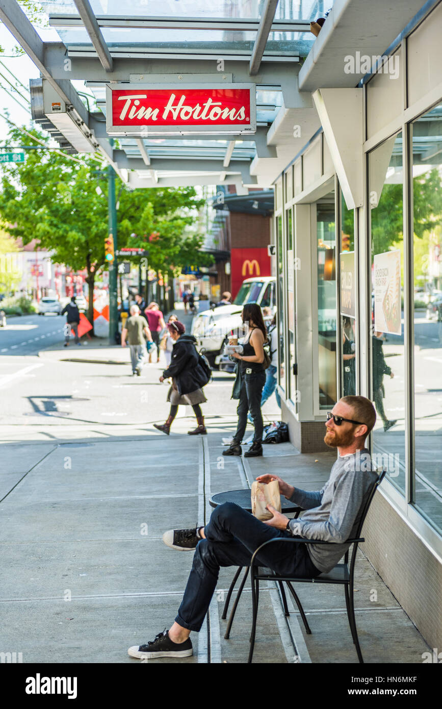 Vancouver, Canada - April 19, 2016: Man sitting by Tim Hortons restaurant with food in downtown Stock Photo