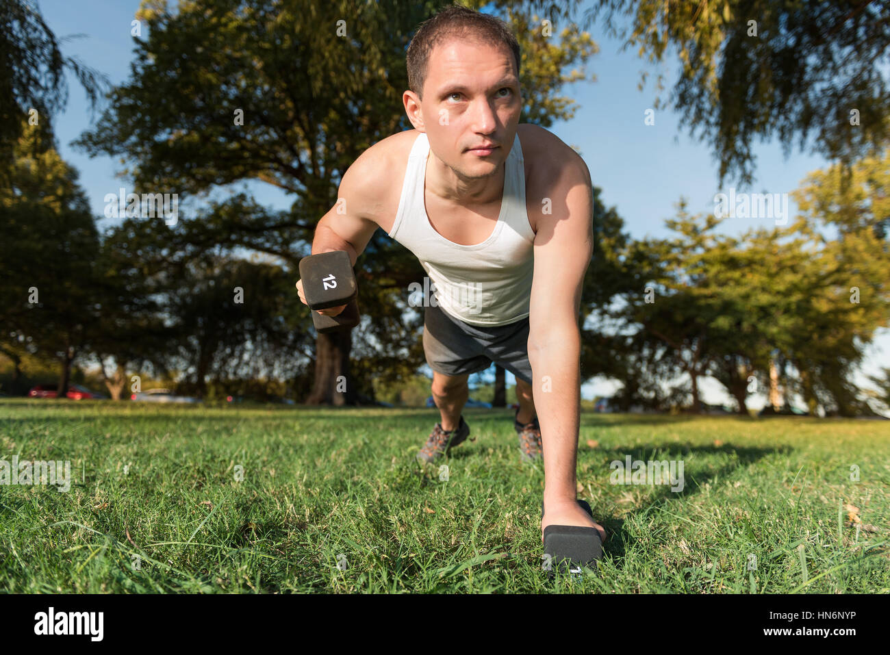Young man performing dumbbell row exercise lifting 12 pound weight in
