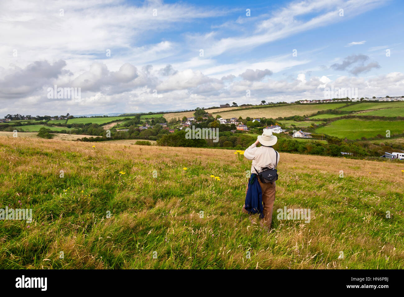 A man taking a photo of the landscape along the South West Coast Path in Dorset, England. Stock Photo