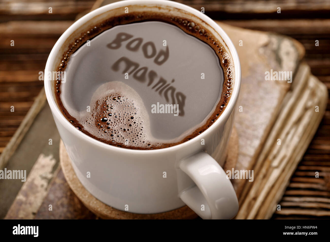 Cup of coffee and old book on wooden background with good morning inscription Stock Photo