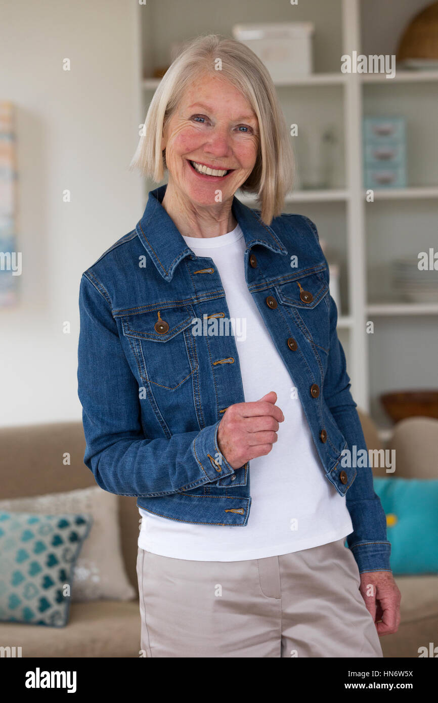 Portrait of a senior woman in her home.She is wearing a denim jacket. Stock Photo