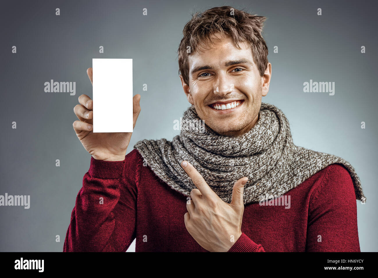 Happy young man with box of medicine pointing finger. Photo of unhealthy man wrapped in scarf. Health care concept Stock Photo