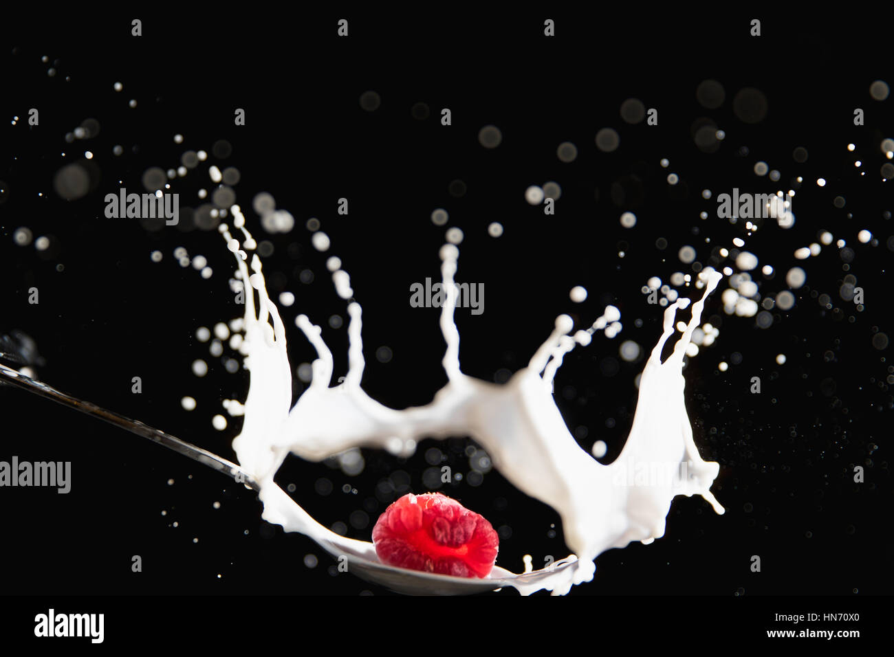 Raspberry drop on spoon with splashing milk Stock Photo - Alamy