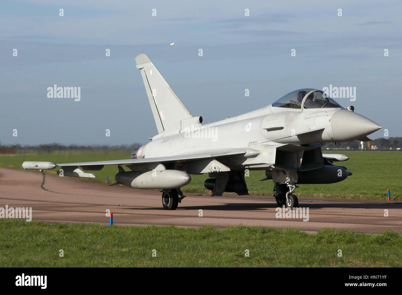 RAF Eurofighter Typhoon operated by 11 Sqn, RAF taxiing out from the shelters at Coningsby for departure as a Tutor overshoots the runway behind. Stock Photo