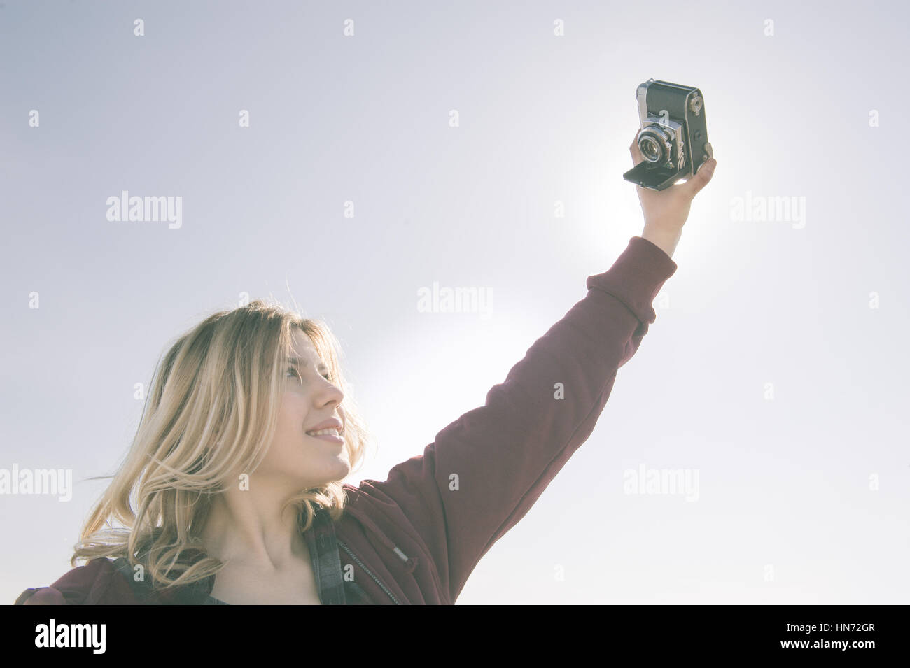 Young beautiful fascinating woman doing a selfie with vintage Kodak retina photo camera Stock Photo