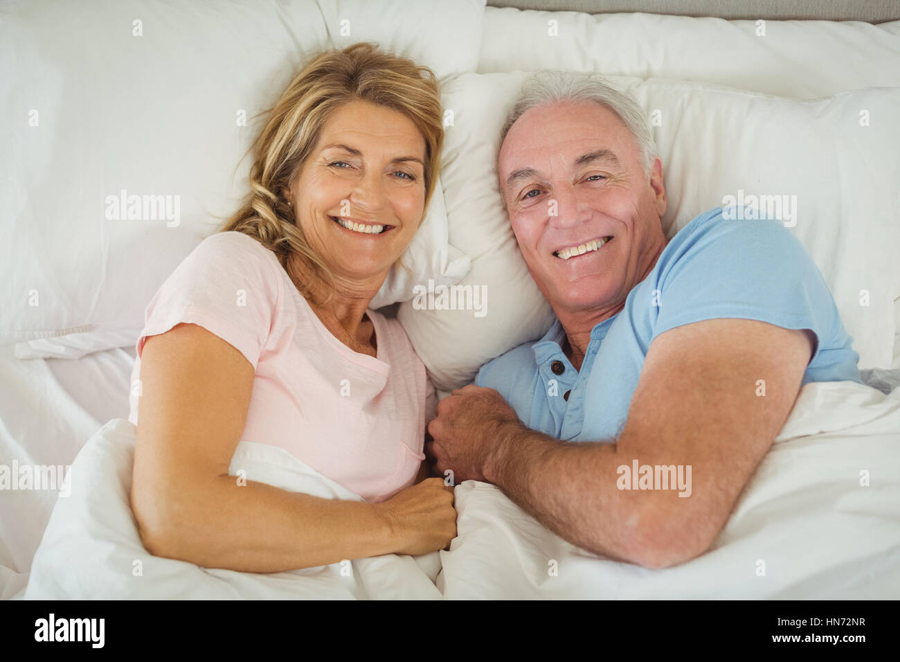 Portrait of happy senior couple lying on bed in bedroom Stock Photo - Alamy