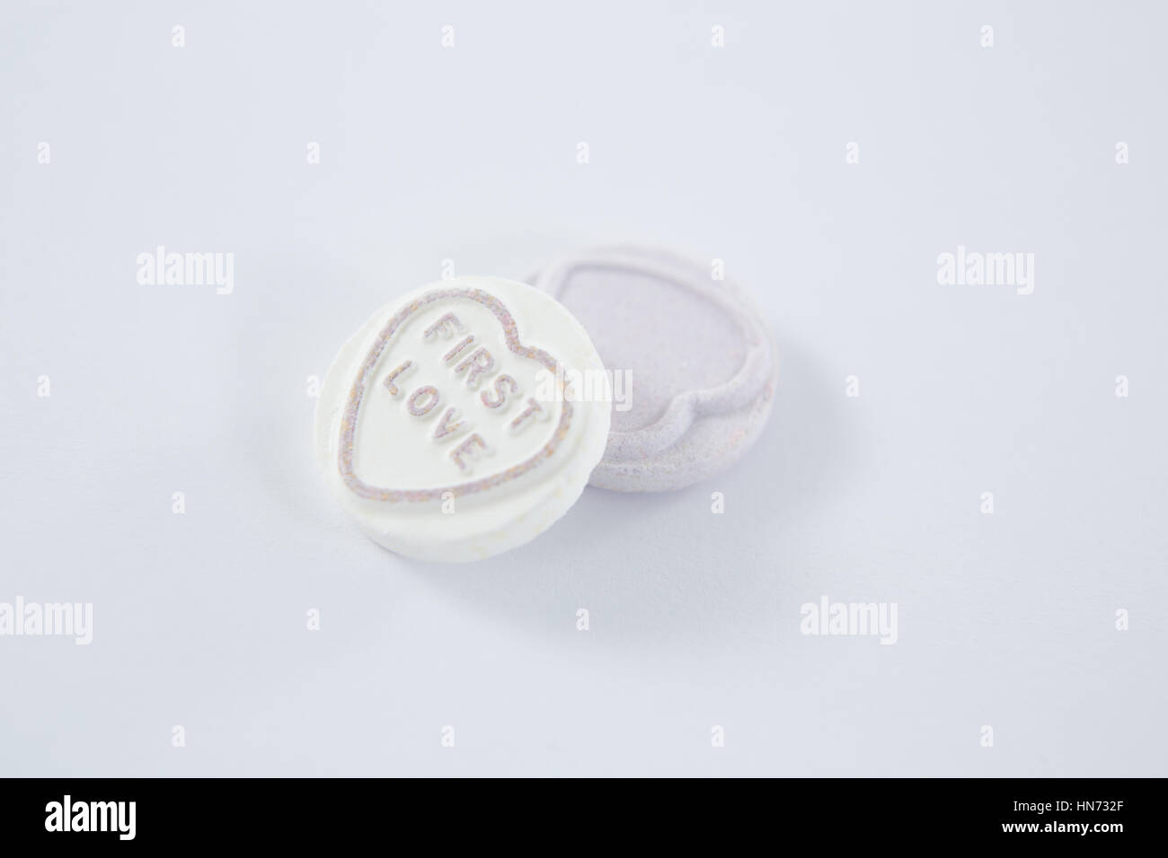 Heart shape confectionery with text first love on white background Stock Photo