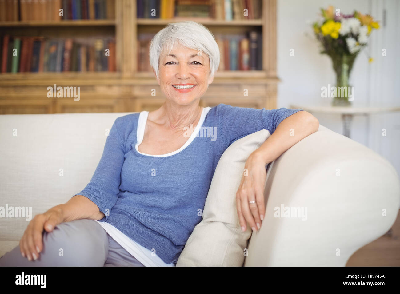 Portrait of smiling senior woman sitting on sofa in living room at home ...