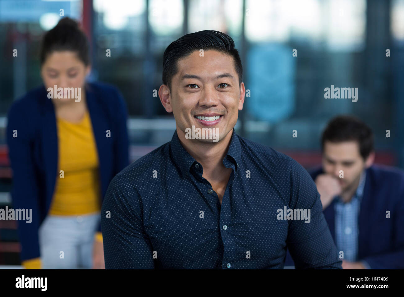 Portrait of male business executive smiling with colleague working in ...