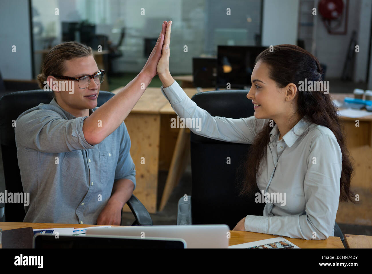 Male and female graphic designers giving high five to each other in ...