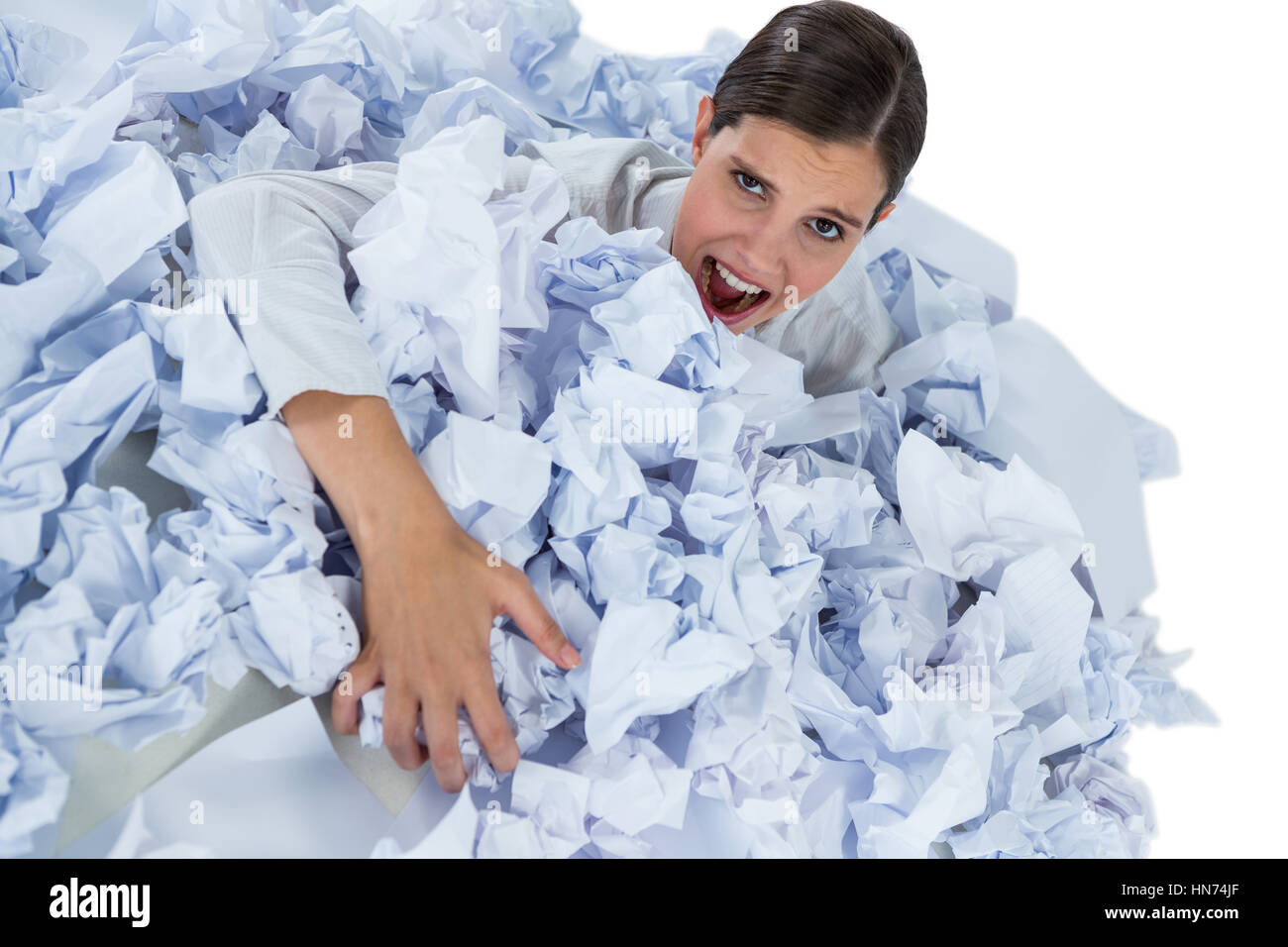 Portrait of unhappy businesswoman in heap crumpled paper against white background Stock Photo