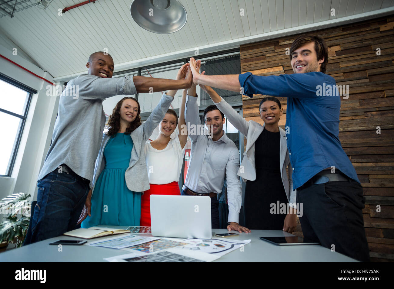 Team of graphic designers giving high five to each other in office ...