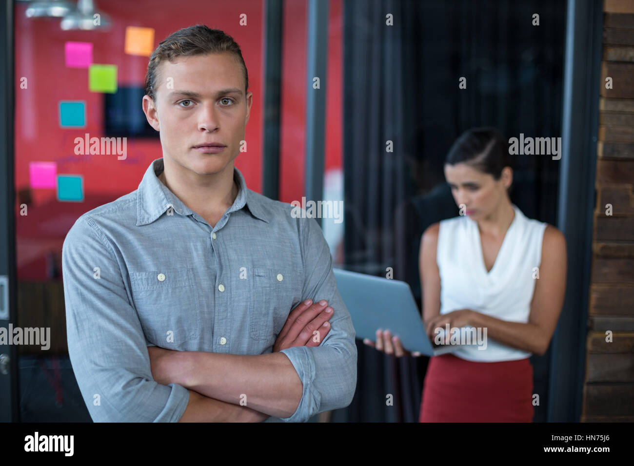 Portrait of confident business executive standing with arms crossed in ...