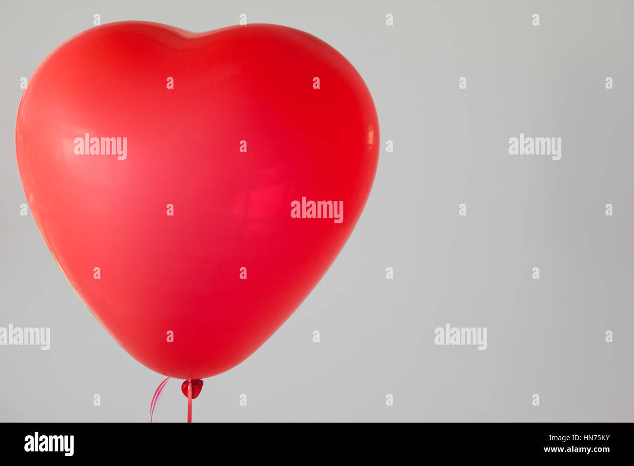 Heart-shaped red balloon against white background Stock Photo - Alamy