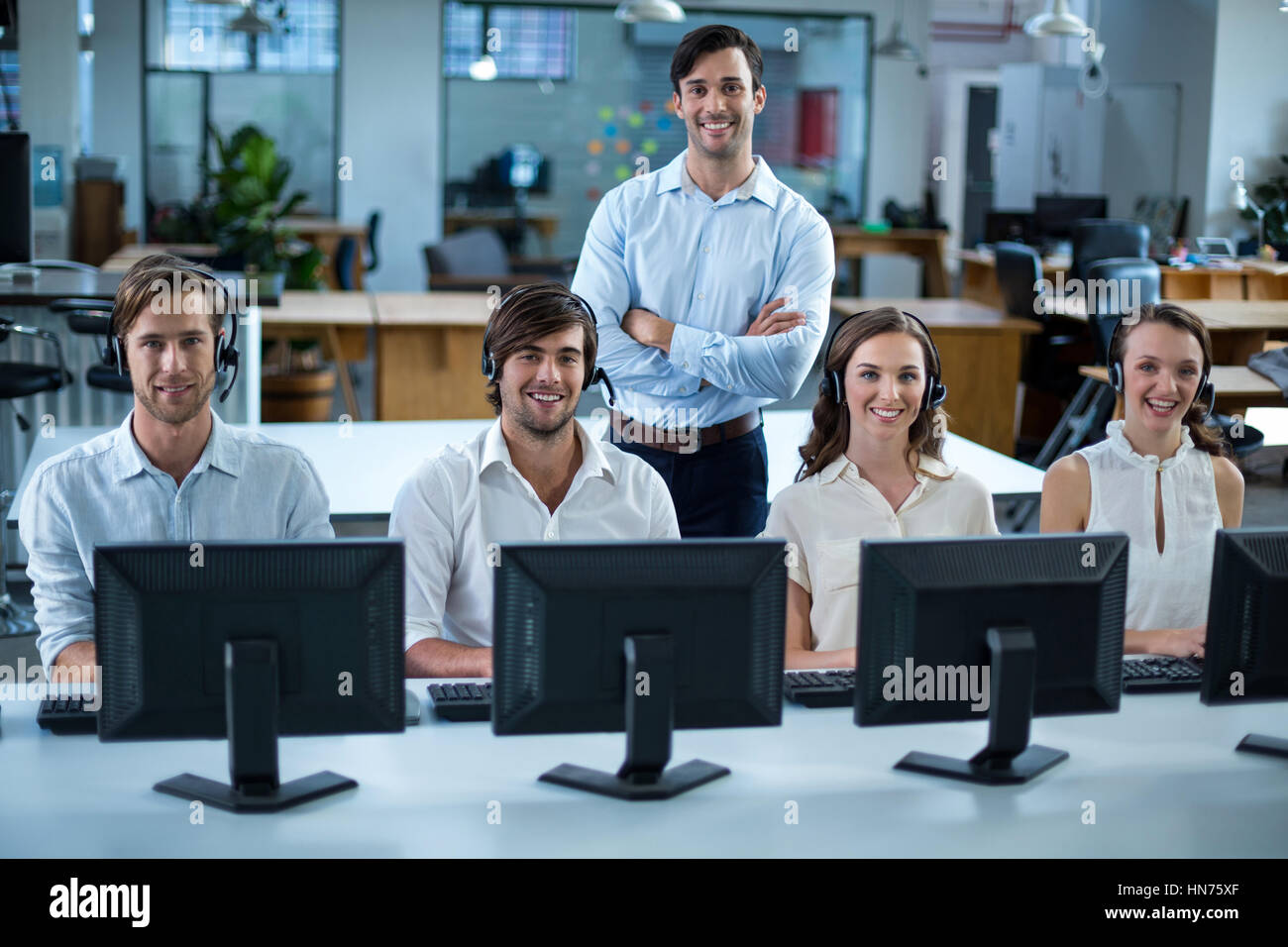 Portrait of business executives with headsets using computer in office ...