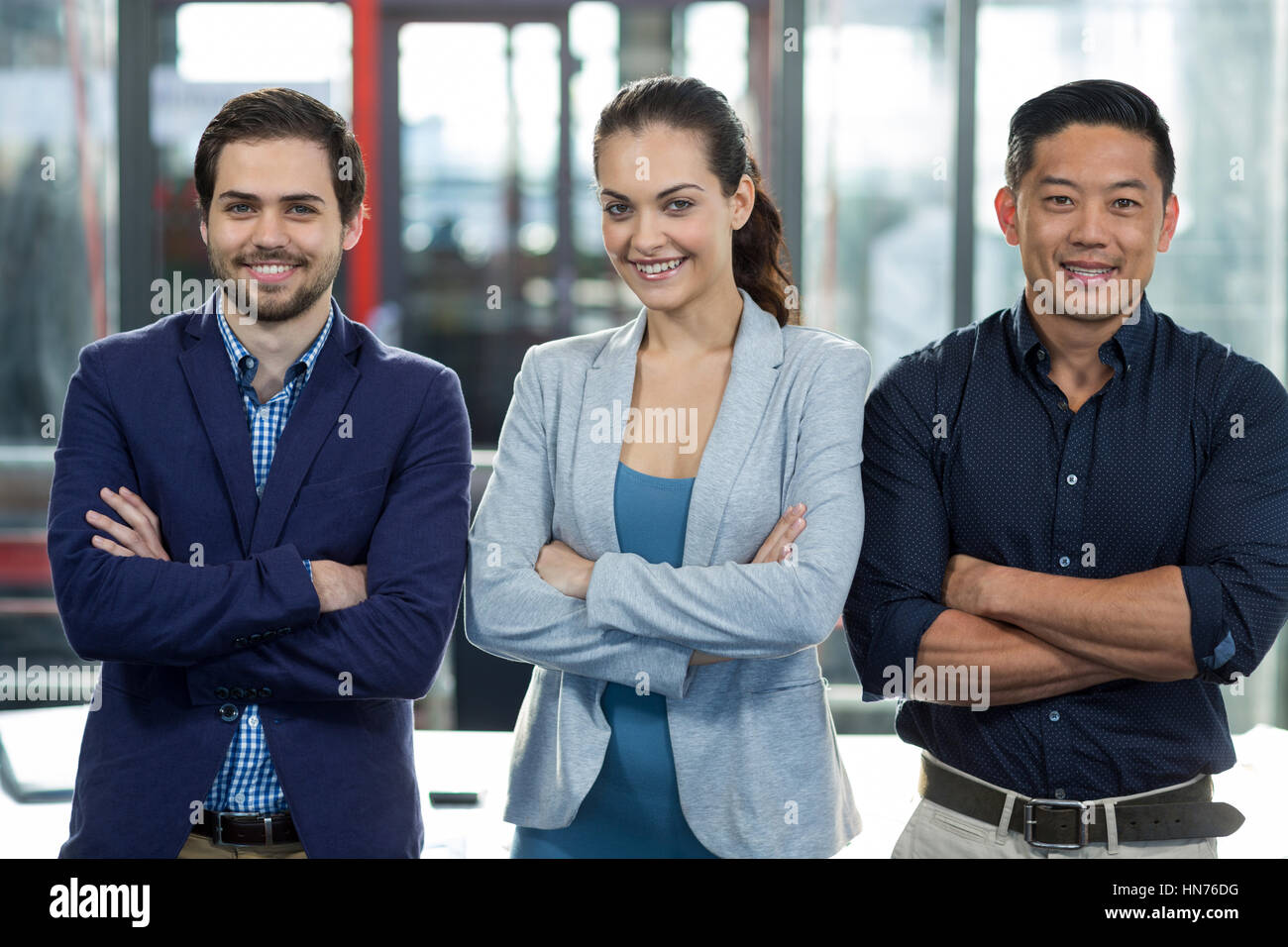 Portrait of smiling businesspeople standing with arms crossed in office ...