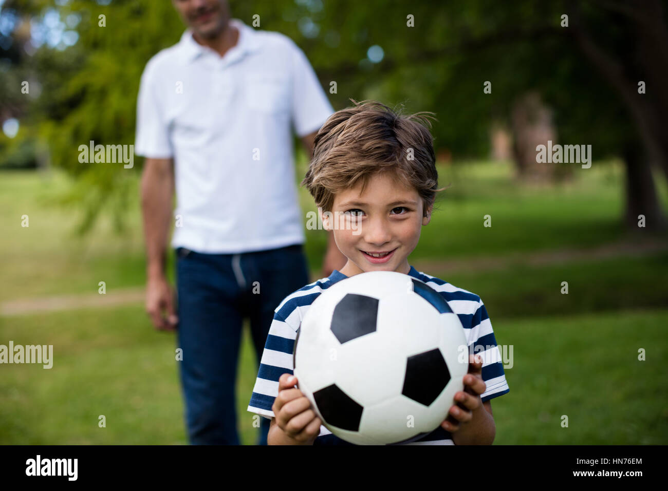 Father and son playing football in park Stock Photo - Alamy
