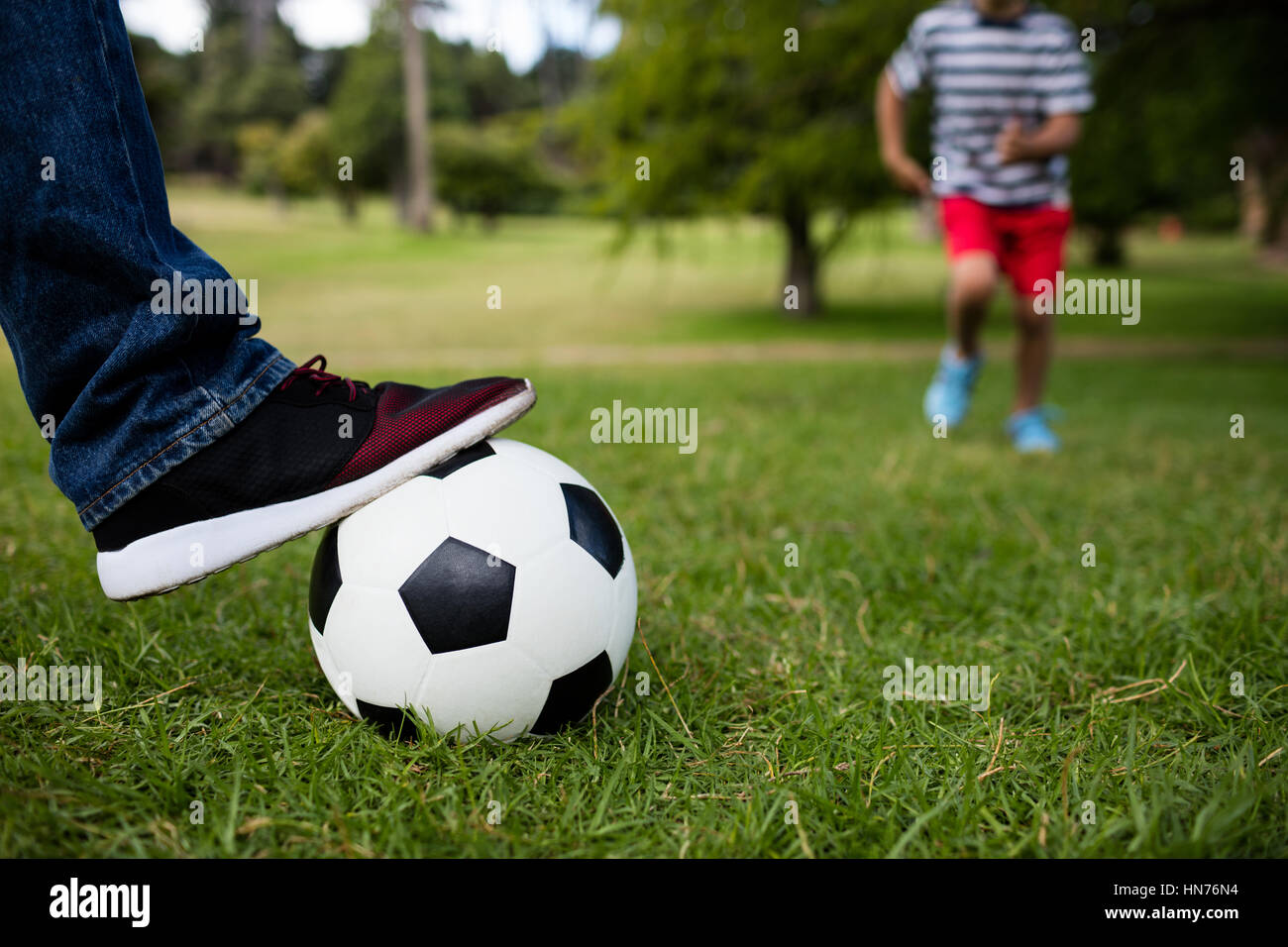 Low section of father and son playing football in park Stock Photo - Alamy