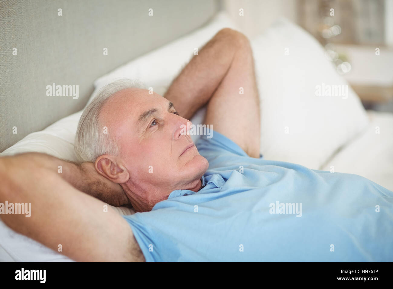 Thoughtful senior man lying on bed in bedroom at home Stock Photo - Alamy