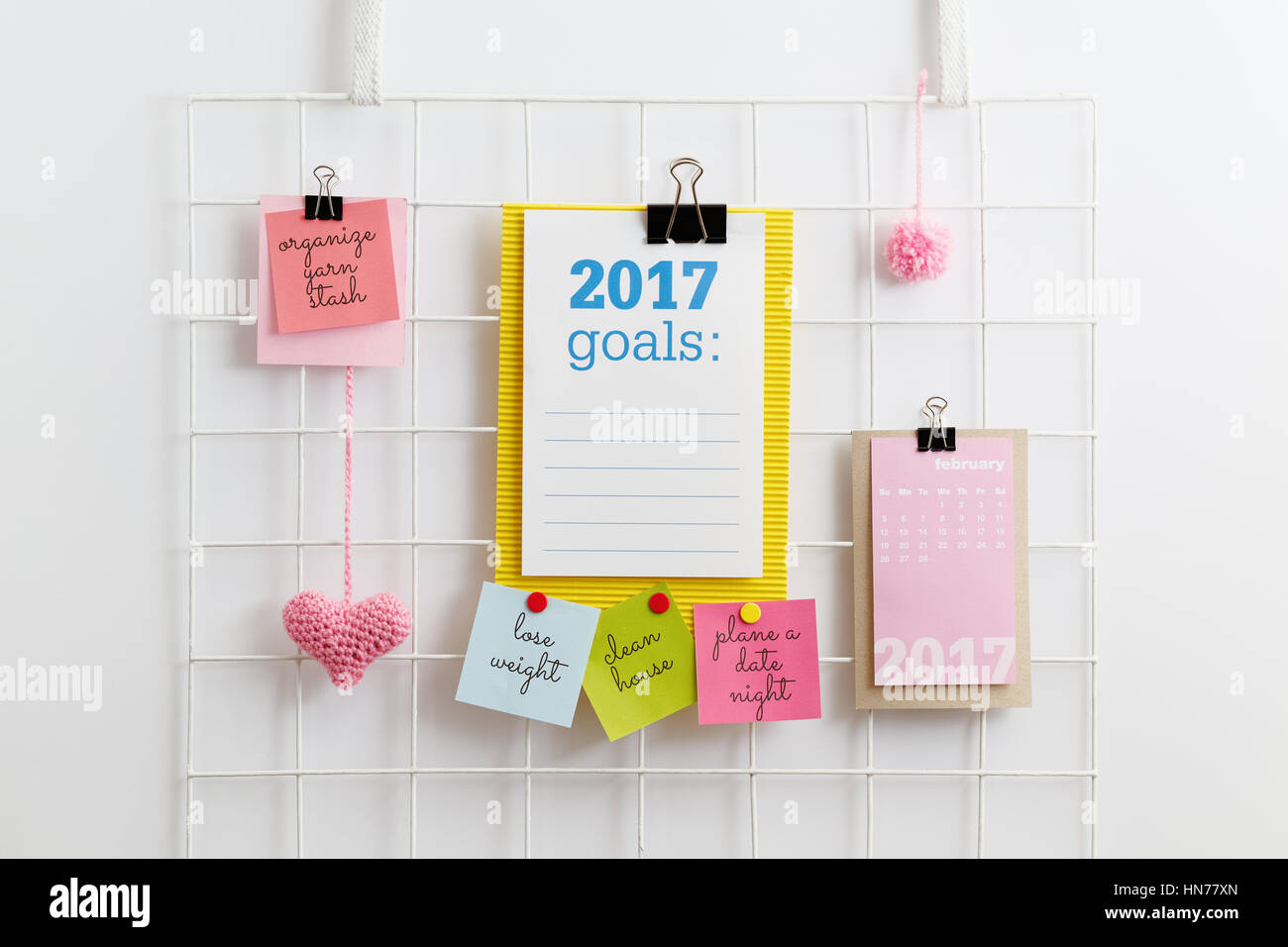 New Year's Resolutions. Paper note written with 2017 GOALS on diy metal mesh grid wall organizer. Metal grid display with pink heart and pom pom. Stock Photo