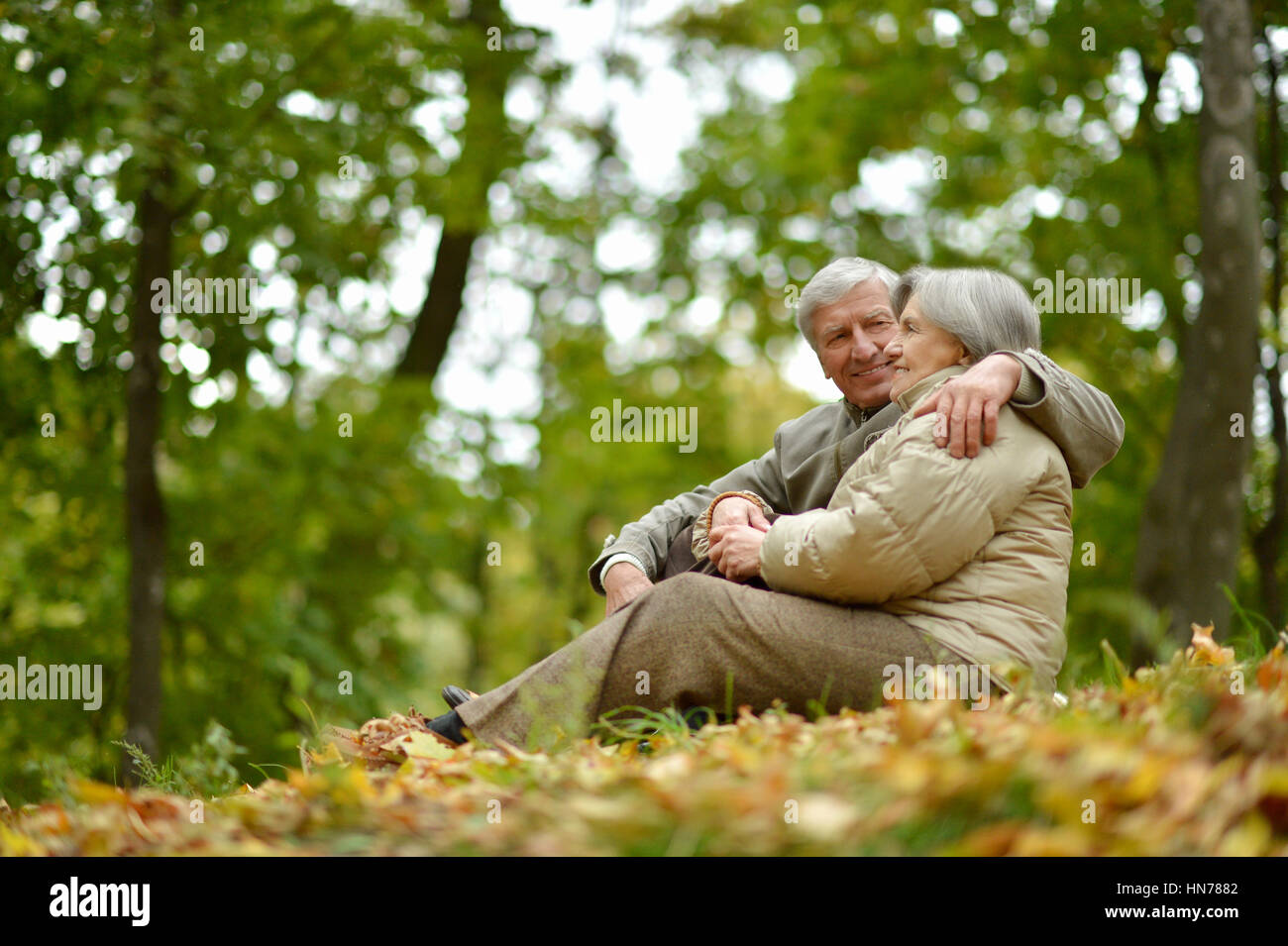 Happy elderly couple sitting in autumn nature Stock Photo - Alamy