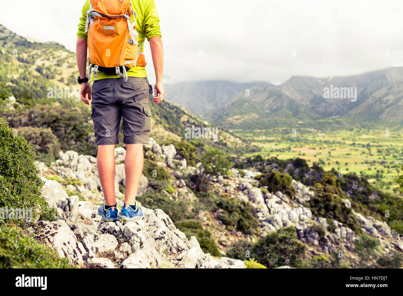 Hiking man looking at beautiful mountains inspirational landscape. Hiker trekking with backpack on rocky trail footpath, admiring a view on valley. He Stock Photo