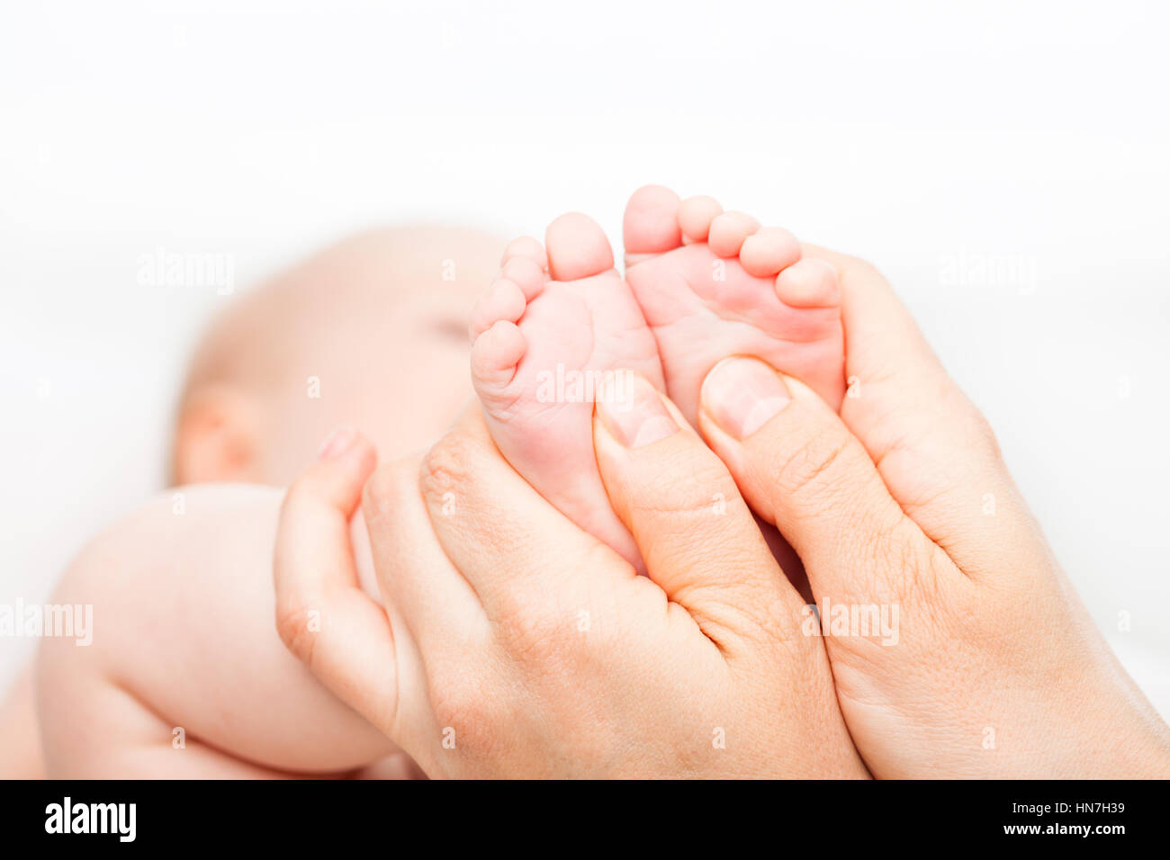 Close-up shot of three month baby girl receiving foot massage from a female  massage therapist. Camera is focused on infant's feet. Face is blurred in  Stock Photo - Alamy