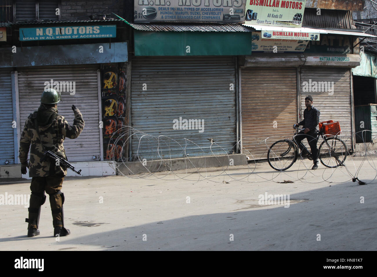 Srinagar, Kashmir. 9th Feb, 2017. An Indian paramilitary trooper stops a cyclist near a barbed wire barricade at a market place during restrictions in Srinagar, summer capital of Kashmir, Feb. 9, 2017. Curfew-like restrictions have been imposed in several of Kashmir to prevent protests and clashes on the fourth death anniversary of Indian parliament-attack convict Mohammed Afzal Guru, officials said Thursday. Credit: Javed Dar/Xinhua/Alamy Live News Stock Photo