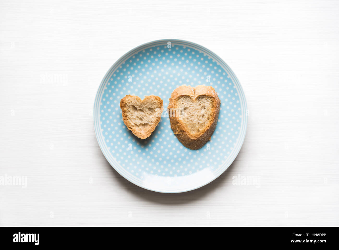 Top view of natural heart-shaped sliced bread on blue plate with white background. Love concept. Stock Photo