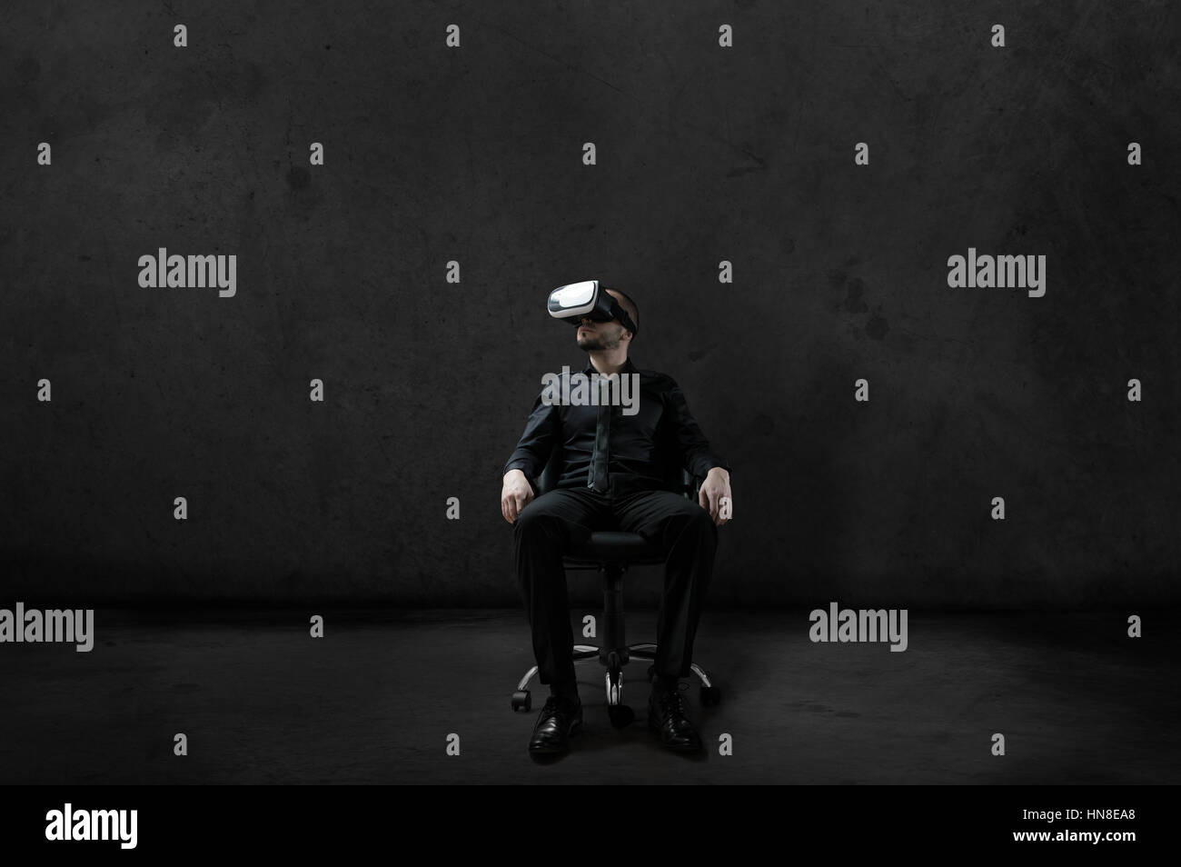 Man with Virtual Reality headset is sitting on chair on wheels in some