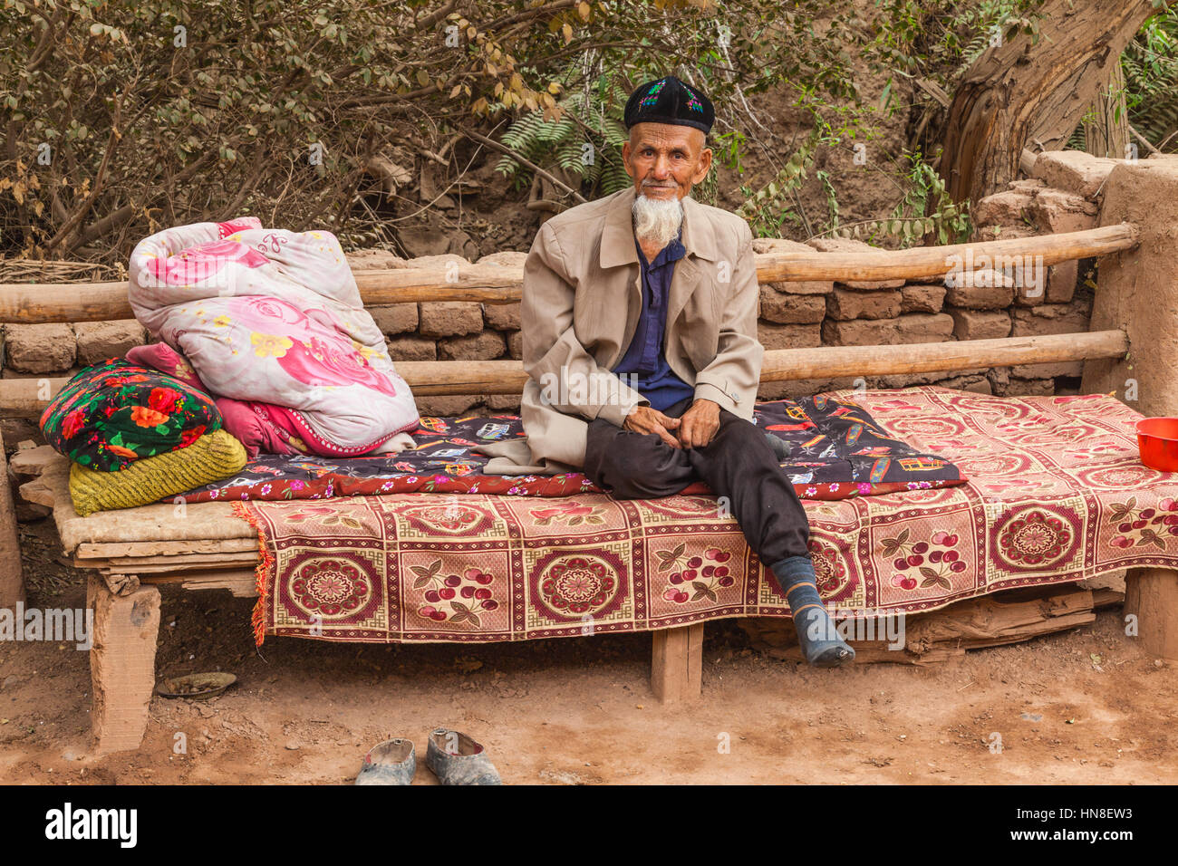 Old Uighur man sitting on bench, Toyuq village, Xinjiang Autonomous Region, China. Stock Photo