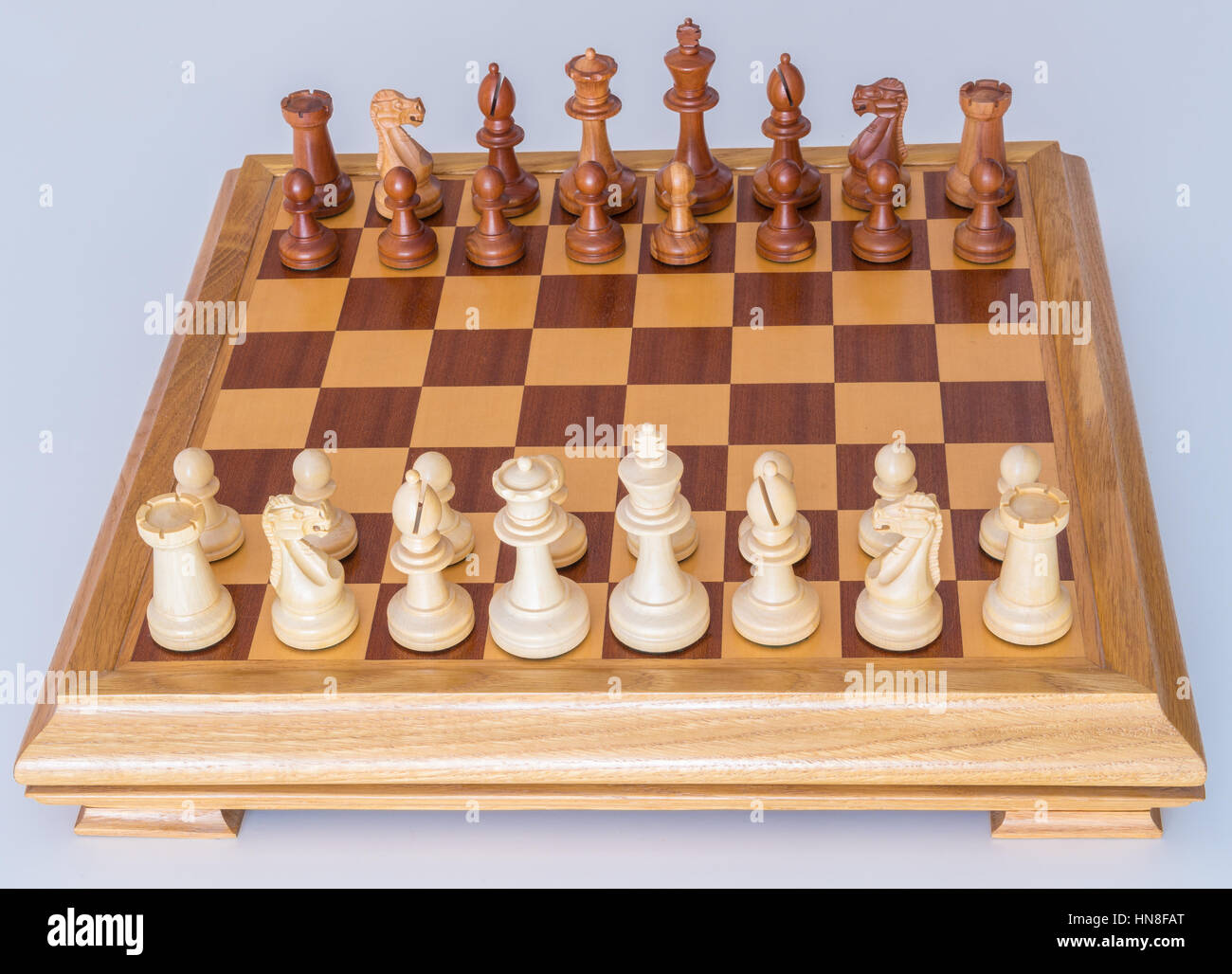 Chess pieces in starting position on a wooden oak Board Stock Photo