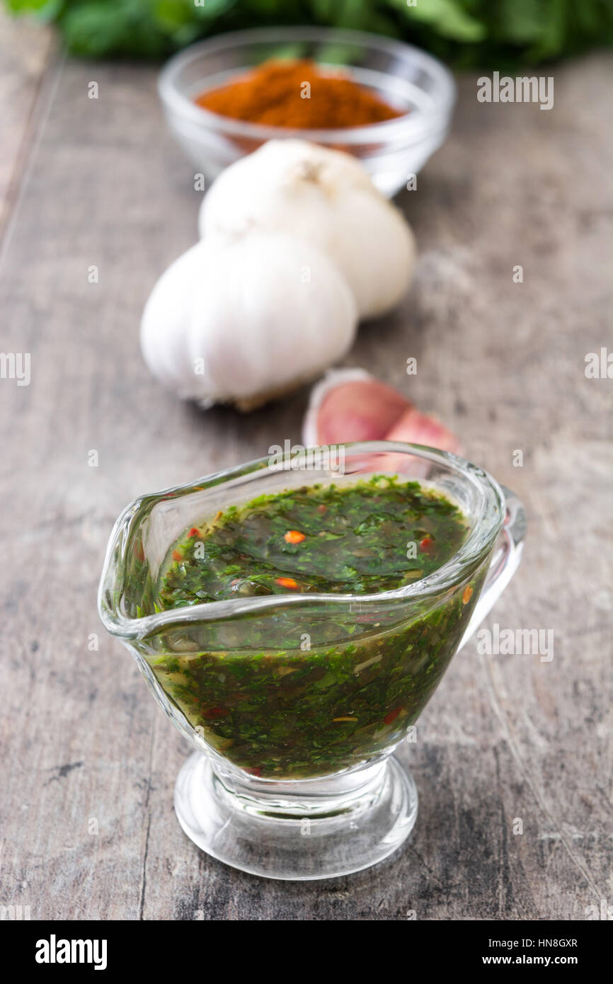 Green Chimichurri Sauce and ingredients on wooden table Stock Photo