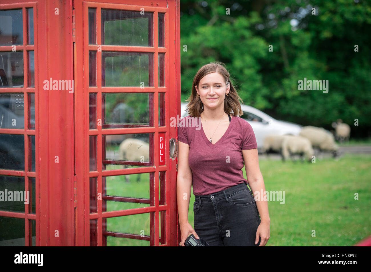 UK, England, Yorkshire - a young girl poses next to an old English telephone booth in Goathland Stock Photo